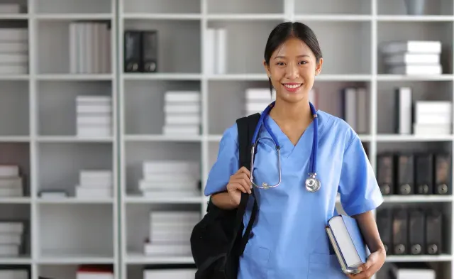 Nursing student smiling in library with bag over shoulder